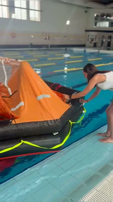 Preparación de una balsa salvavidas desde el borde de la piscina durante las prácticas TCP